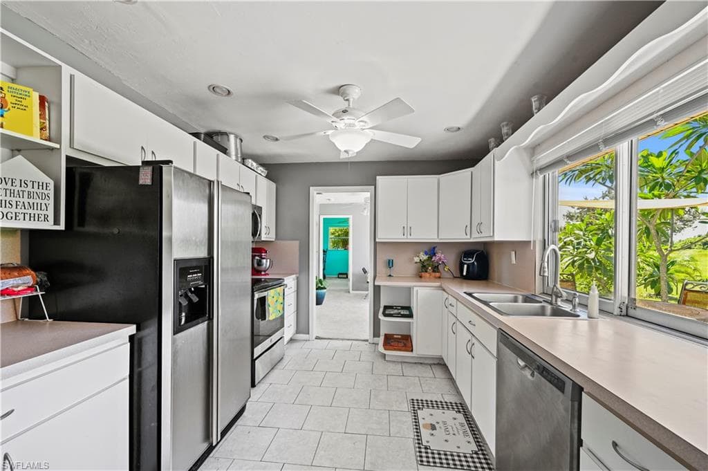 Kitchen featuring white cabinetry, ceiling fan, appliances with stainless steel finishes, and sink
