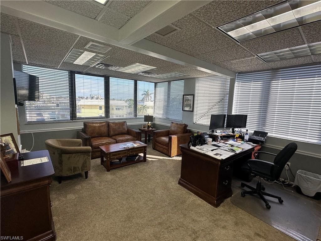 Office with carpet flooring and a paneled ceiling