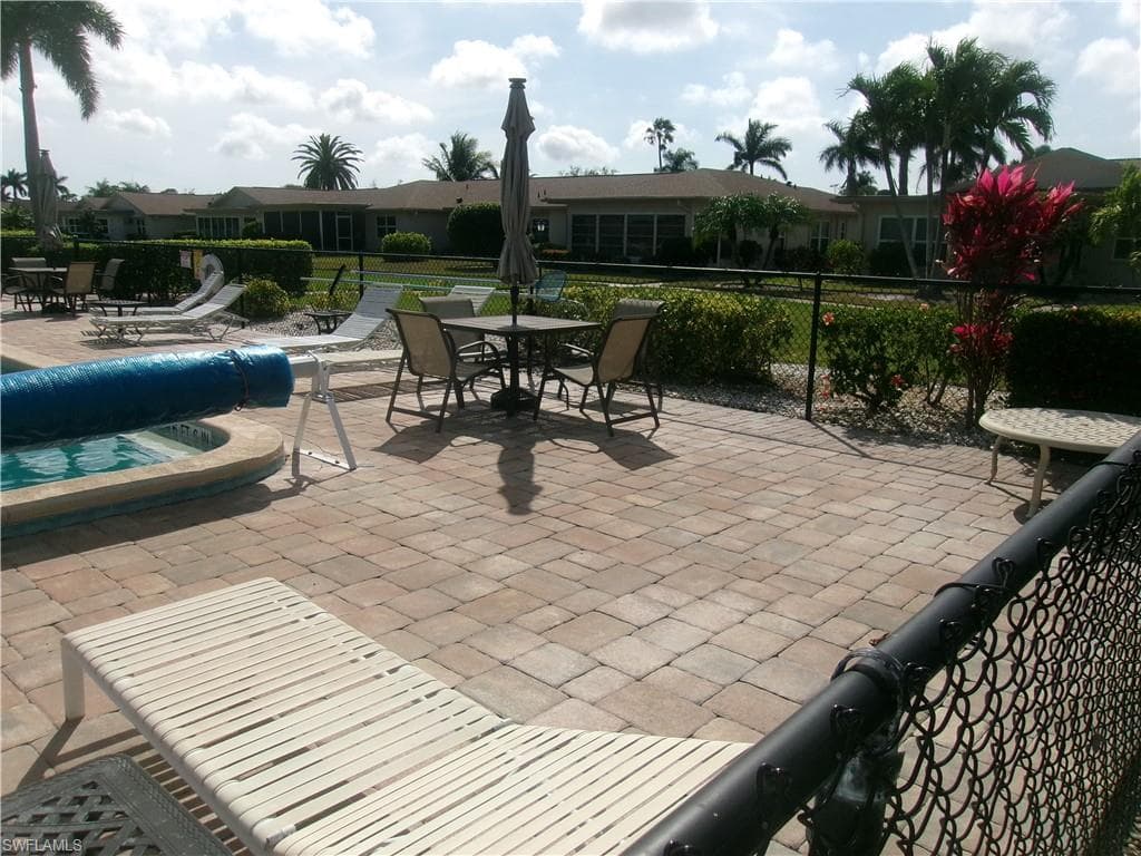 View of patio / terrace with a hot tub, a community pool, and fence