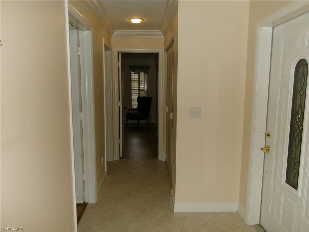Corridor featuring light tile patterned flooring, crown molding, and baseboards