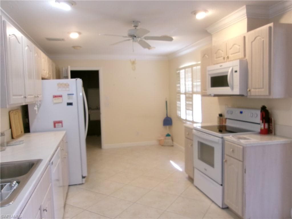 Kitchen featuring ornamental molding, light countertops, white appliances, and white cabinets