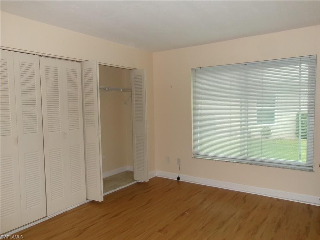 Unfurnished bedroom featuring baseboards, a closet, and wood finished floors