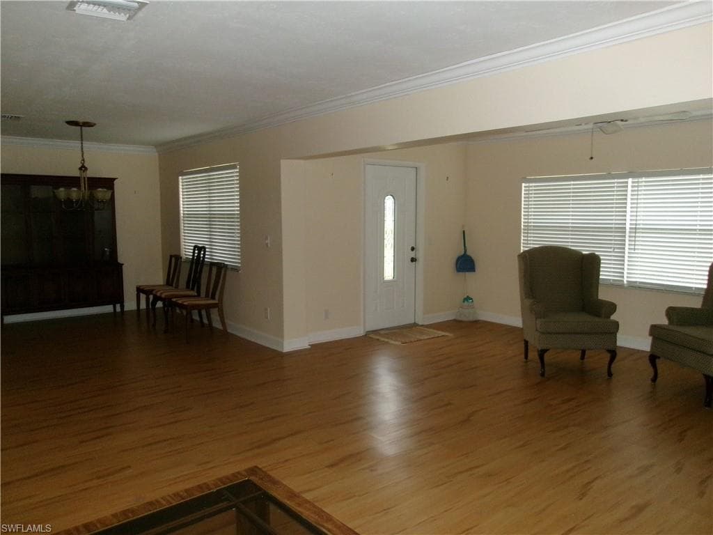 Foyer featuring an inviting chandelier, baseboards, ornamental molding, and wood finished floors