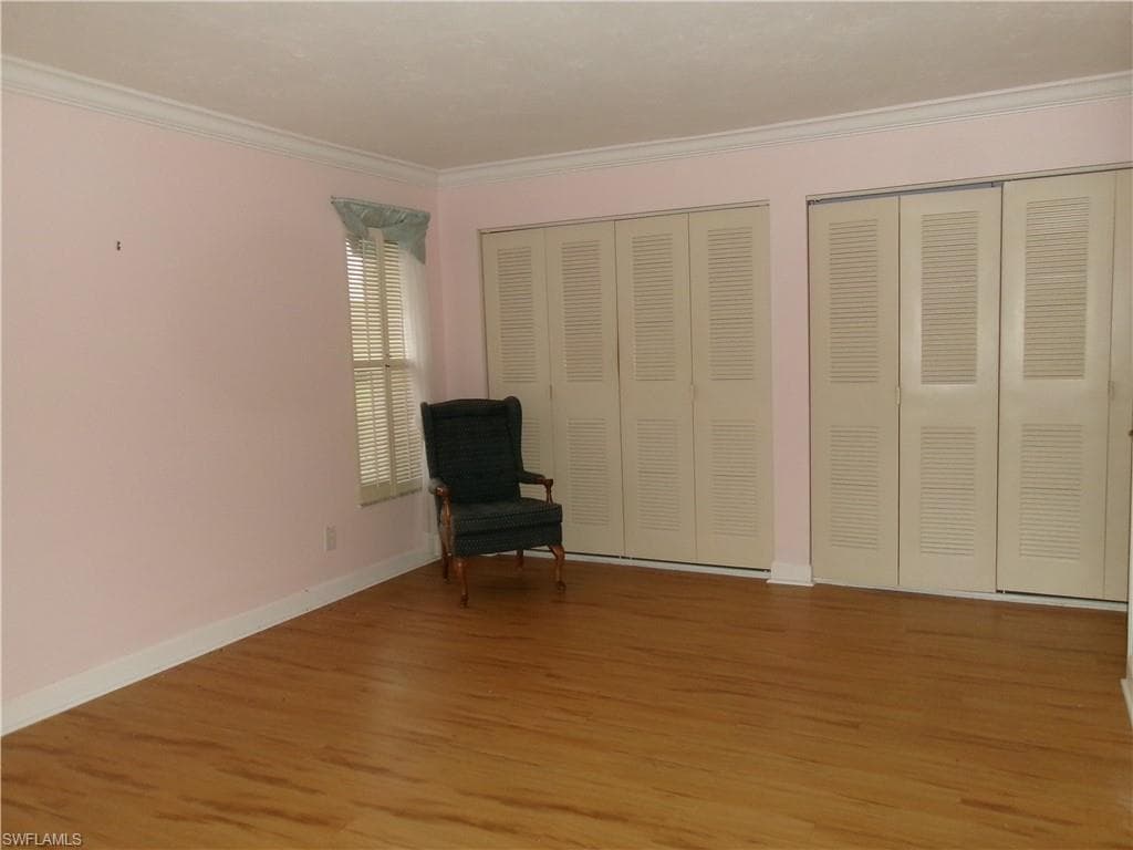 Unfurnished room with light wood-style floors, baseboards, and ornamental molding