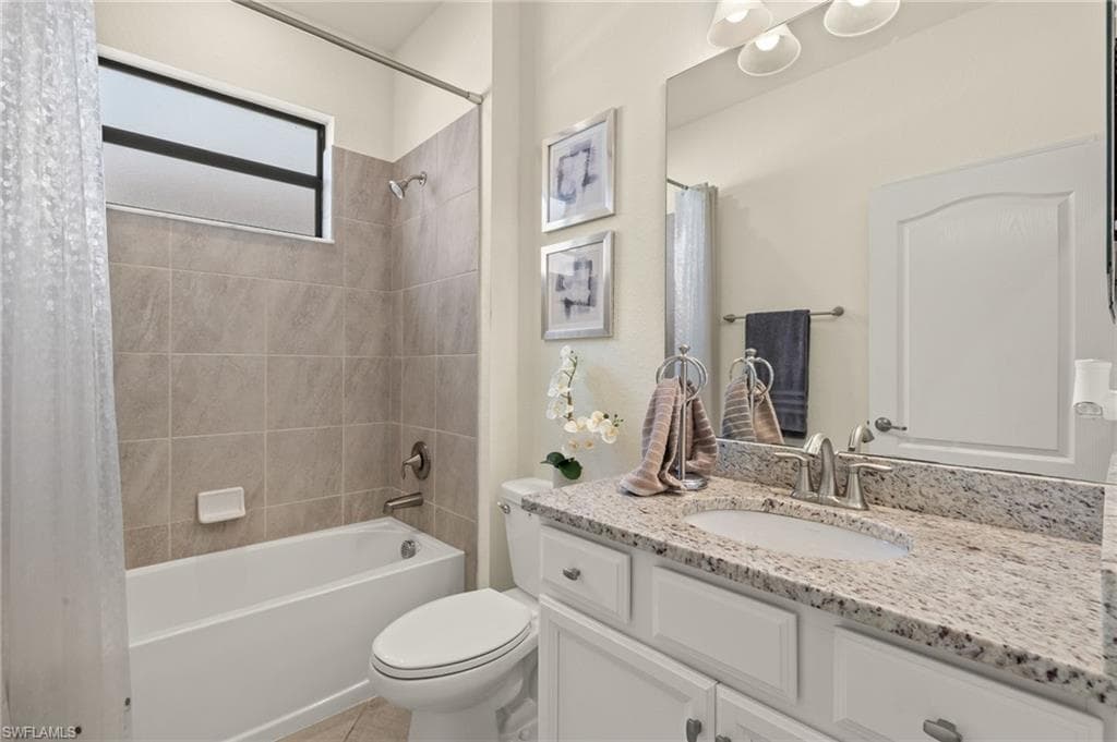 Full bathroom with shower / bath combination with curtain, vanity, tile patterned flooring, and toilet