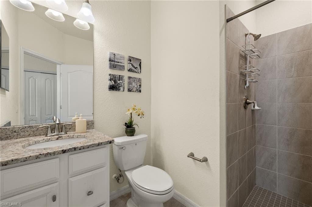 Bathroom with vanity, tiled shower, and toilet