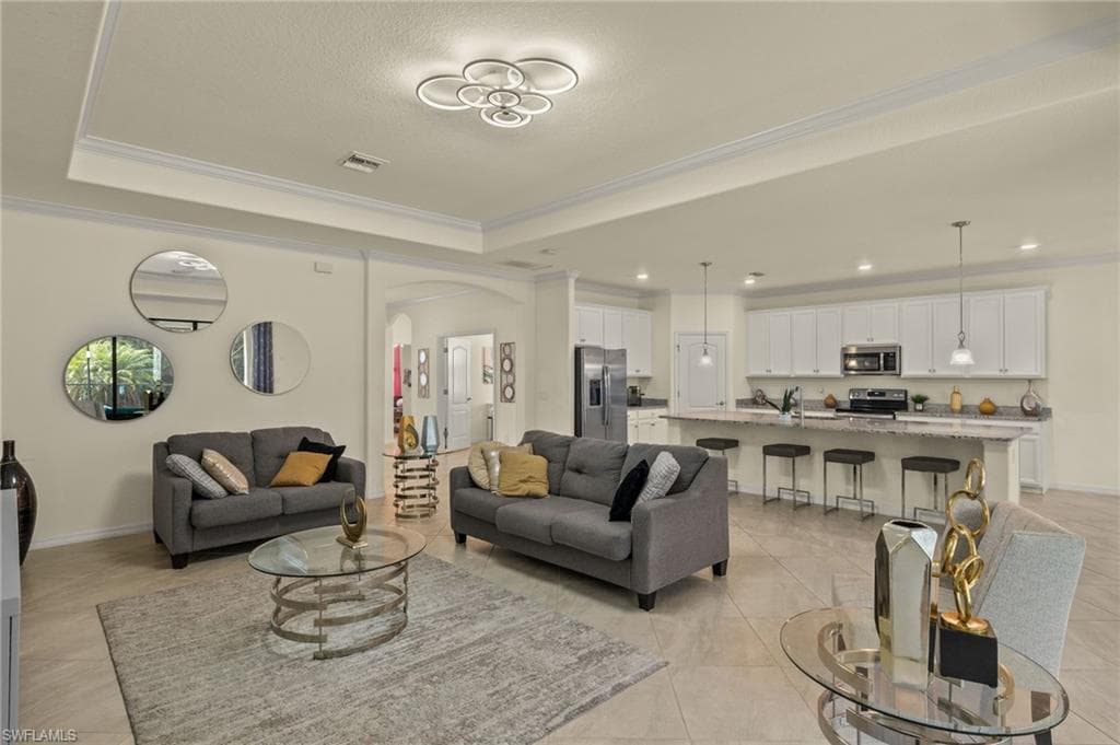 Tiled living room with a tray ceiling, ornamental molding, and sink