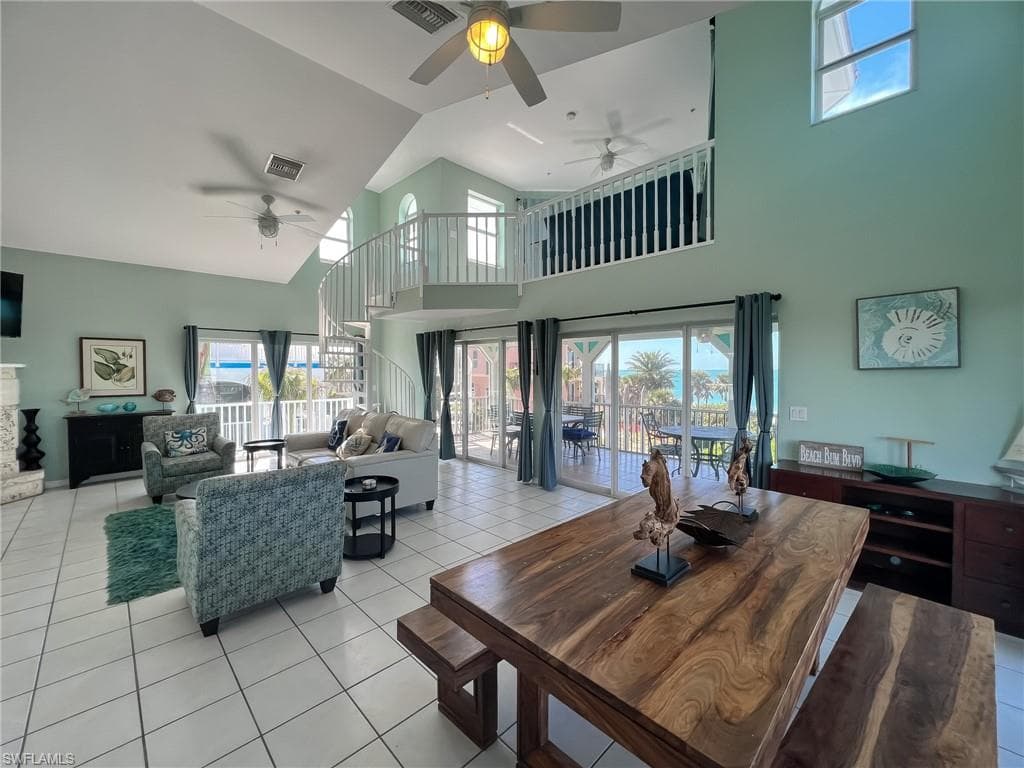 Dining room with light tile patterned floors, high vaulted ceiling, a fireplace, and visible vents