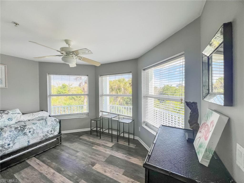 Bedroom with ceiling fan, baseboards, and dark wood-type flooring