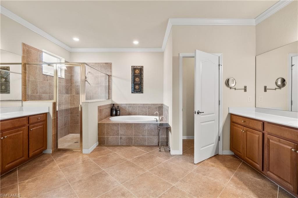 Full master bathroom with crown molding, a stall shower, a jet spa tub, and double vanities and two walk-in master closets