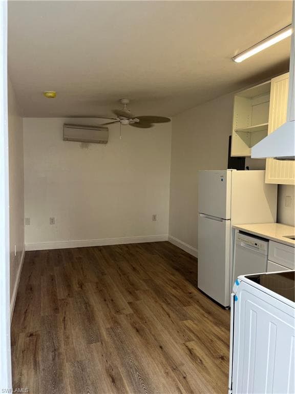 Kitchen with a ceiling fan, dark wood-style floors, white cabinets, and washer / dryer