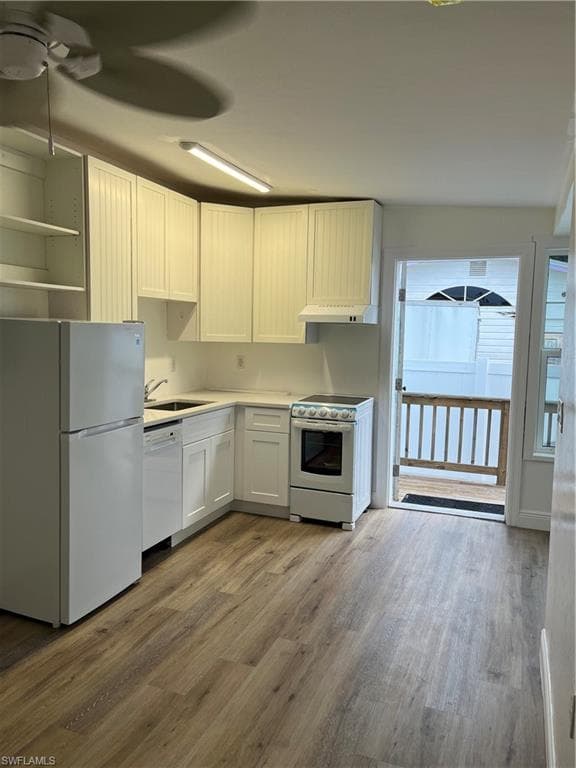 Kitchen featuring refrigerator, stove, wood finished floors, dishwashing machine, and ceiling fan