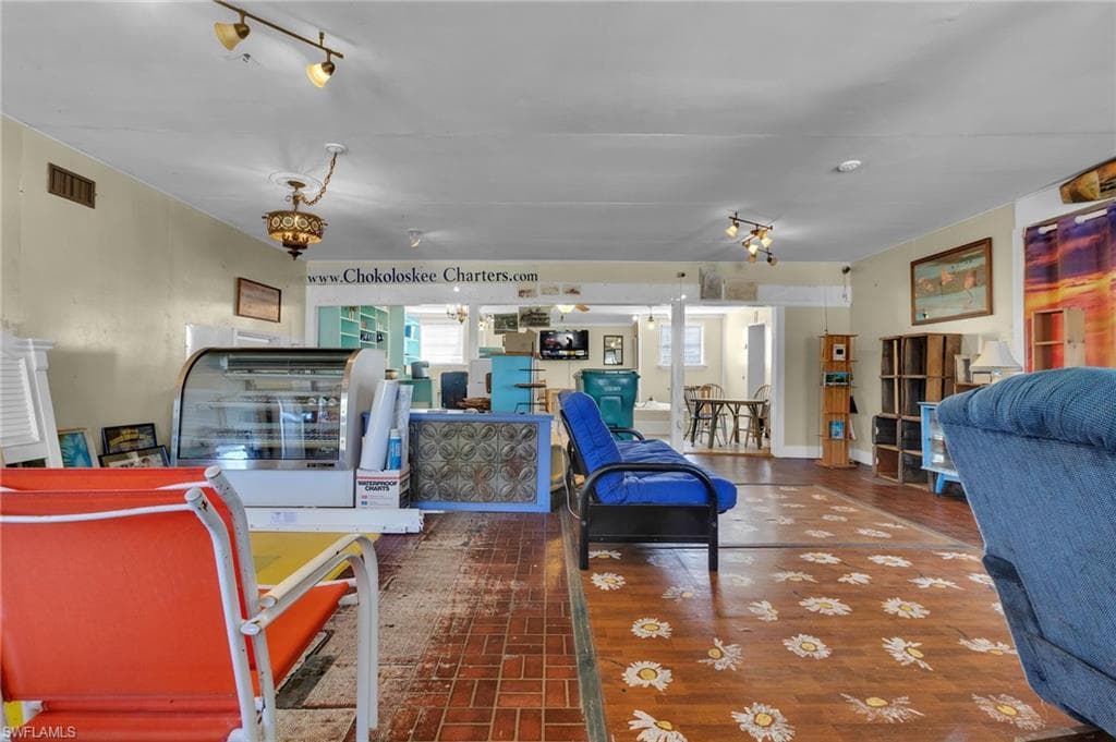 Living area with wood finished floors, visible vents, and track lighting
