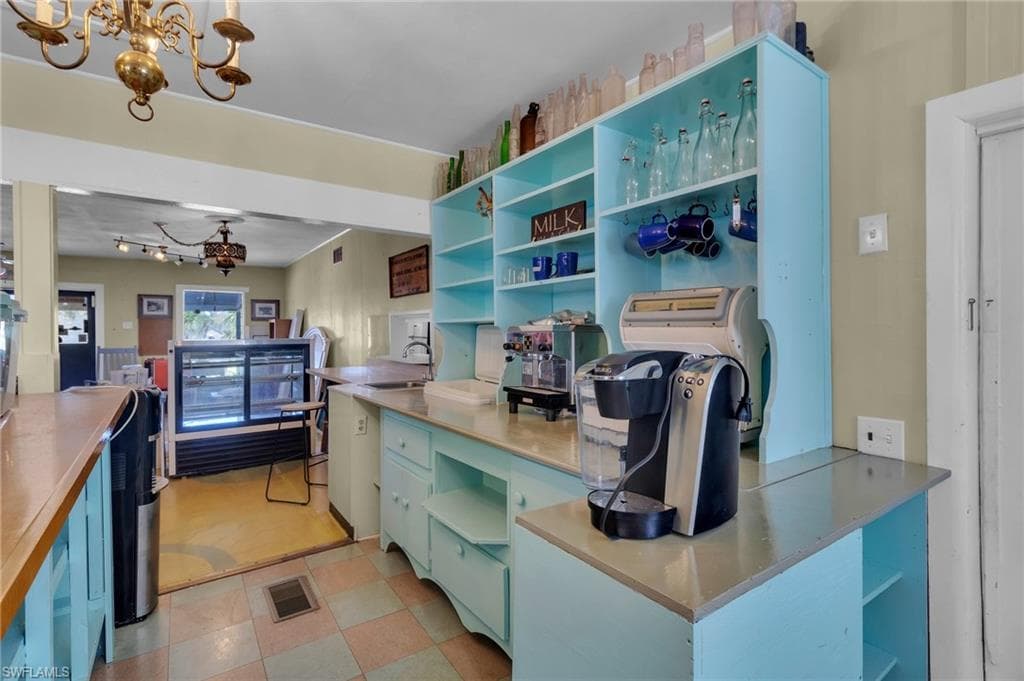 Kitchen with decorative light fixtures, a sink, an inviting chandelier, and open shelves