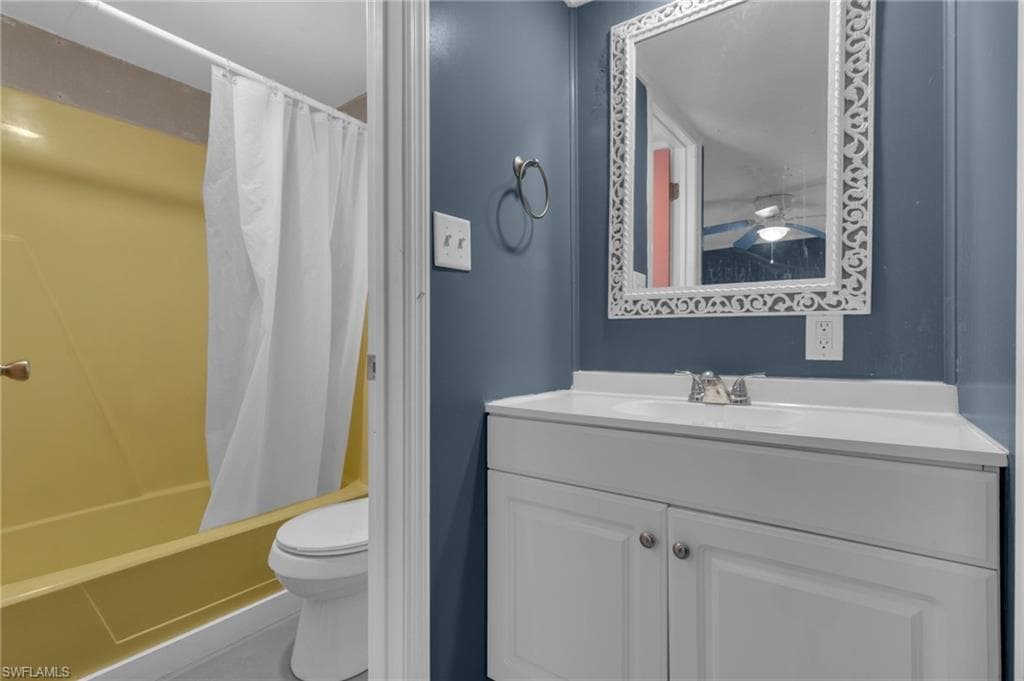 Bathroom featuring toilet, shower / tub combo, and vanity