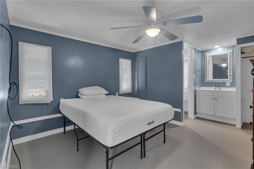 Bedroom featuring ceiling fan, wood floors, ensuite bath, and baseboards