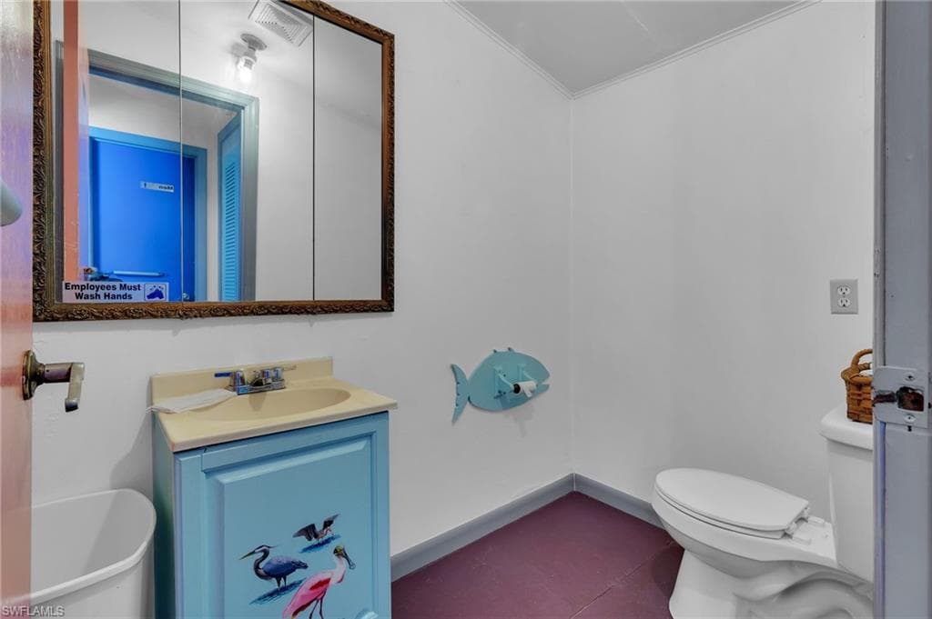 Bathroom featuring visible vents, baseboards, toilet, crown molding, and vanity