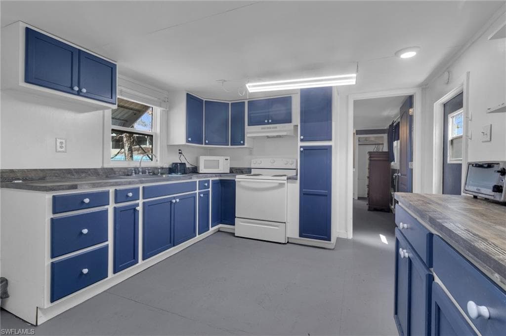 Kitchen featuring a sink, blue cabinets, white appliances, and under cabinet range hood