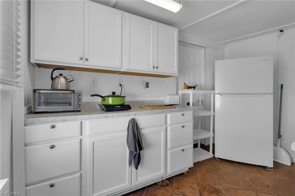 Kitchen with freestanding refrigerator, white cabinets, light countertops, and a toaster