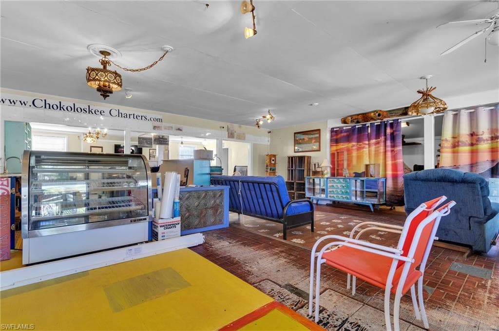 Living room featuring brick floor and a ceiling fan