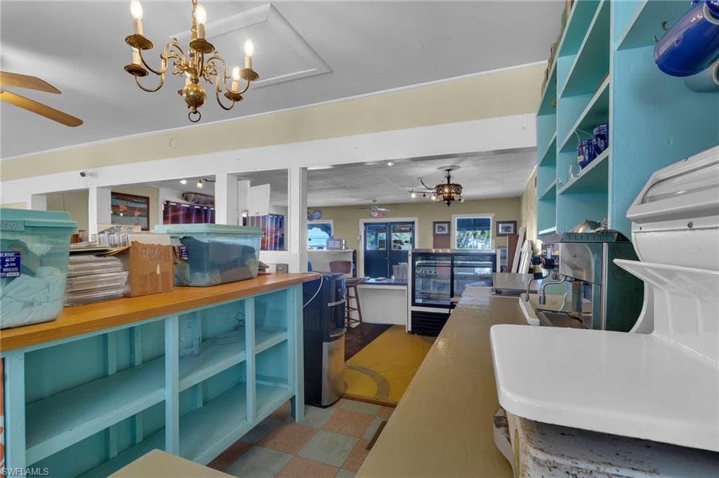 Kitchen featuring open shelves, tile patterned floors, open floor plan, and ceiling fan with notable chandelier