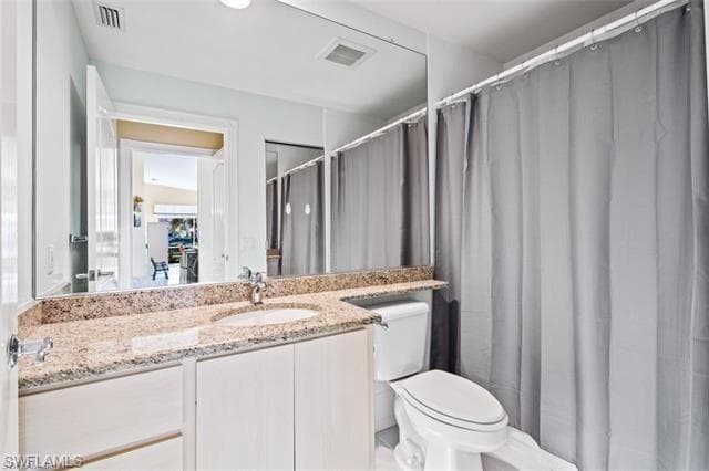 Full bath with toilet, vanity, and visible vents