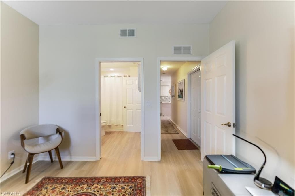 Office space with light wood-style flooring, visible vents, and baseboards