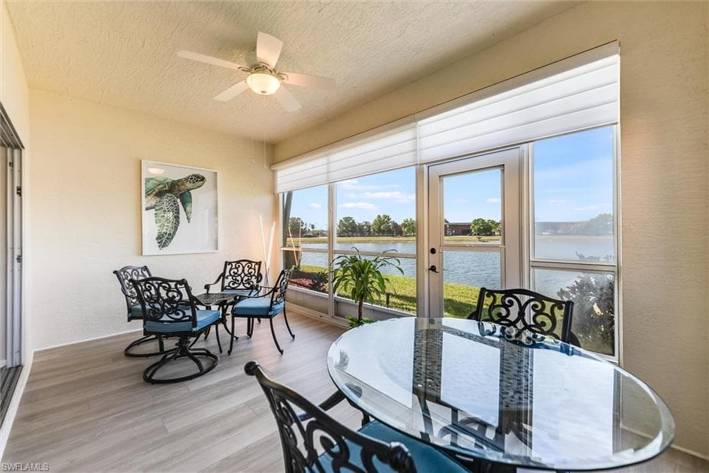 Dining space featuring a water view, ceiling fan, a textured ceiling, and wood finished floors