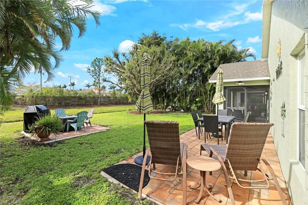 View of yard with a patio area, a fenced backyard, outdoor dining area, and a sunroom