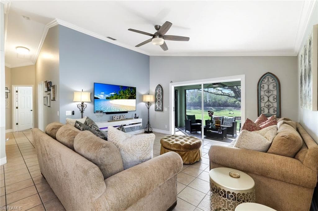 Living area featuring lofted ceiling, light tile patterned floors, and ornamental molding