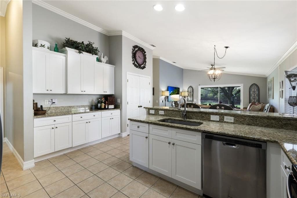 Kitchen with lofted ceiling, ornamental molding, white cabinetry, a sink, and dishwasher