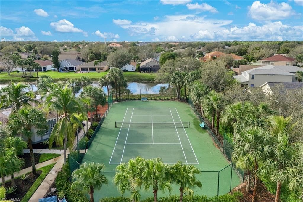View of sport court featuring a water view, a residential view, and fence