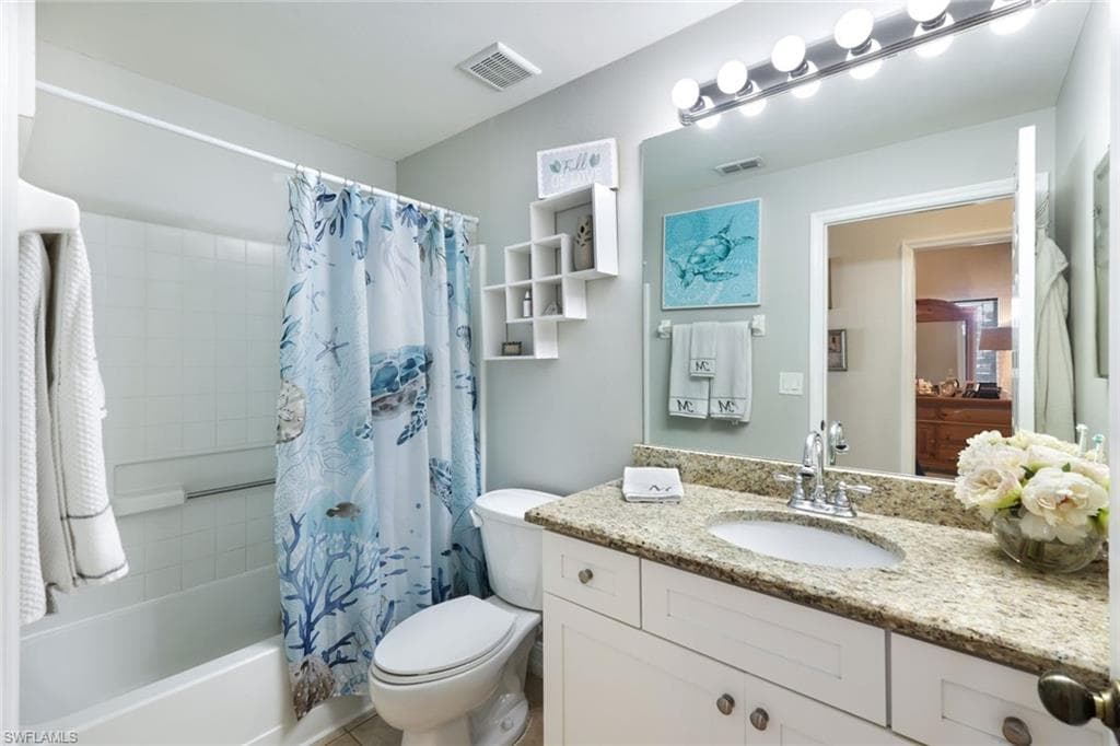 Bathroom featuring toilet, shower / tub combo, vanity, and visible vents