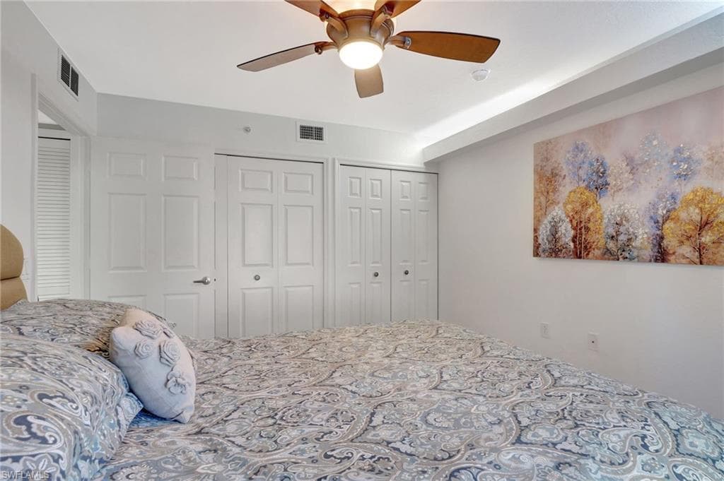 Bedroom with visible vents, ceiling fan, and two closets
