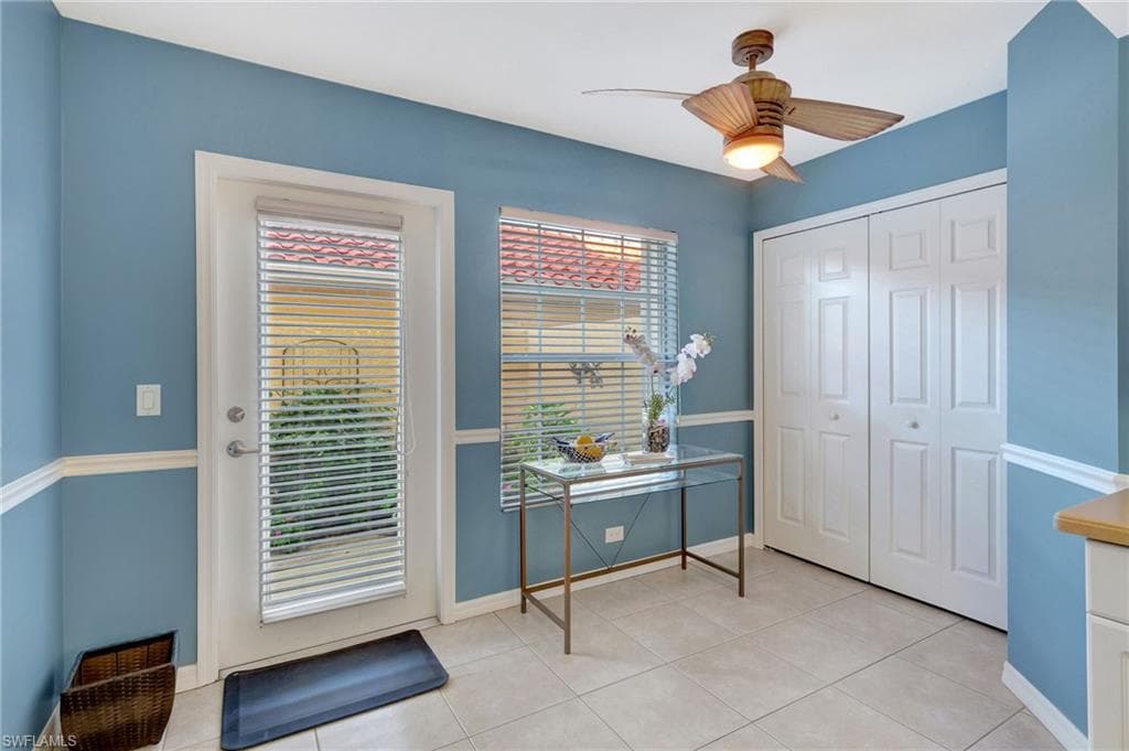 Doorway to outside with baseboards, a ceiling fan, and light tile patterned flooring