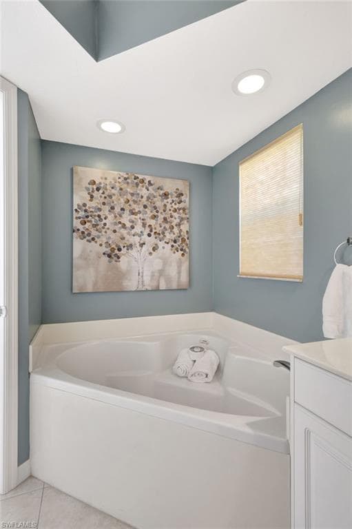 Bathroom with a wealth of natural light, vanity, a bath, and tile patterned floors
