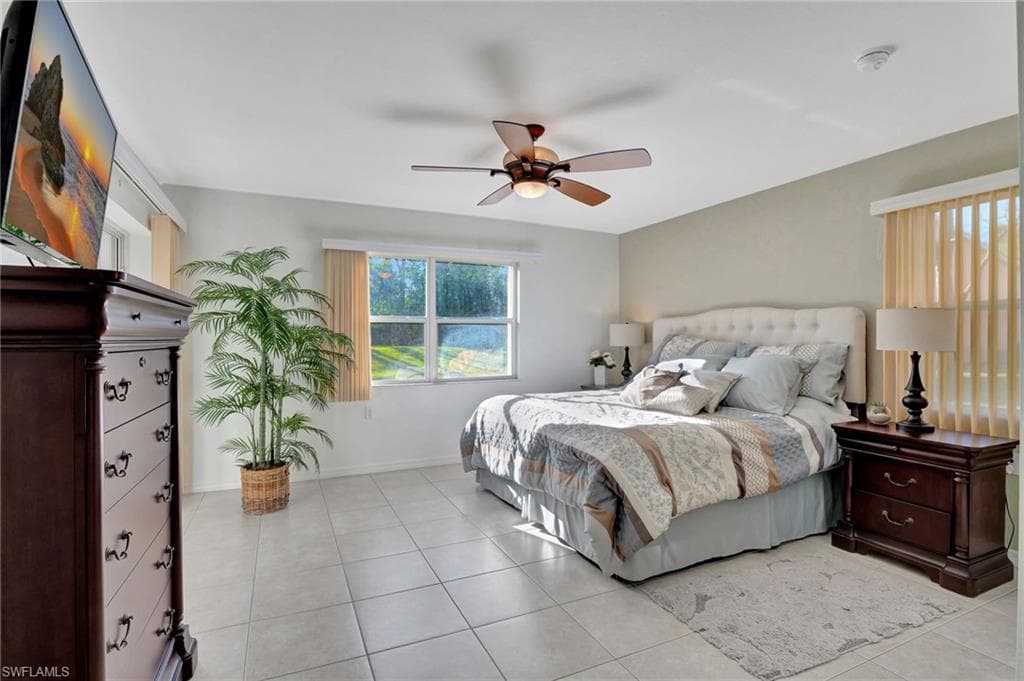 Bedroom featuring a ceiling fan, light tile patterned flooring, and baseboards