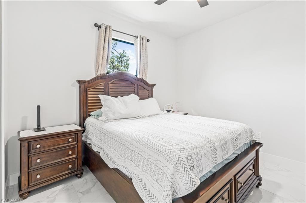 Bedroom featuring marble finish floor, ceiling fan, and baseboards