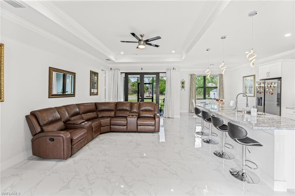 Living area featuring baseboards, marble finish floor, ornamental molding, french doors, and a tray ceiling