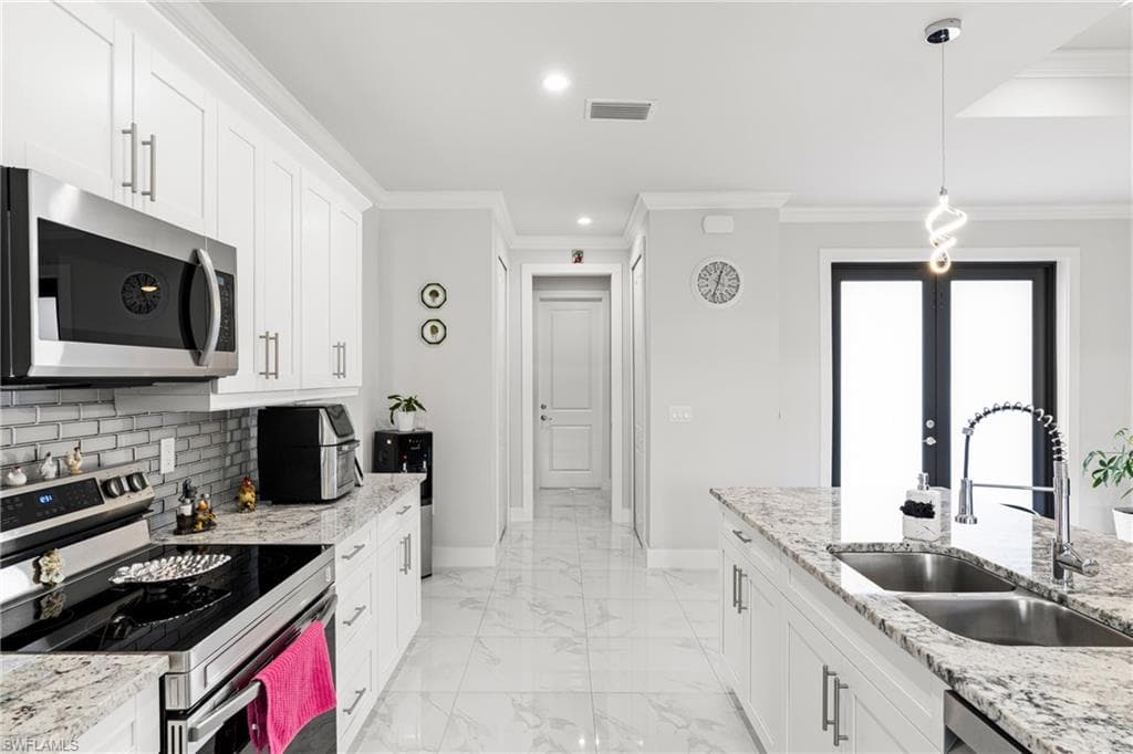 Kitchen with baseboards, visible vents, a sink, stainless steel appliances, and backsplash