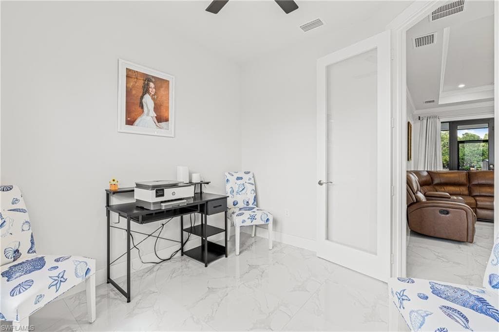 Office space with marble finish floor, visible vents, and crown molding
