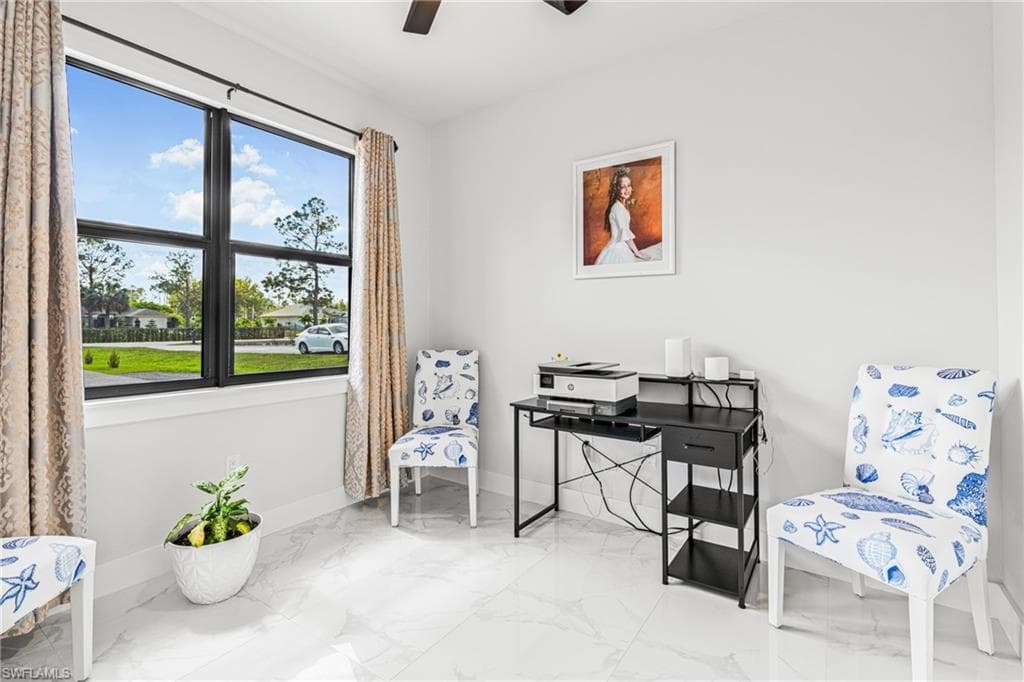 Living area featuring a ceiling fan, marble finish floor, and baseboards
