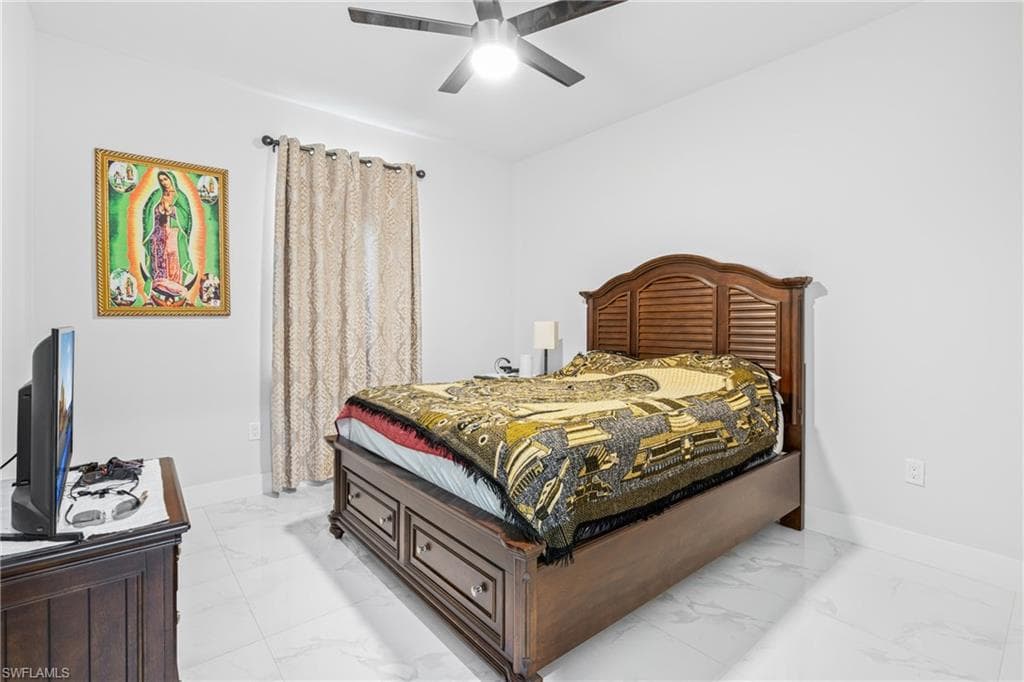 Bedroom featuring marble finish floor, baseboards, and a ceiling fan