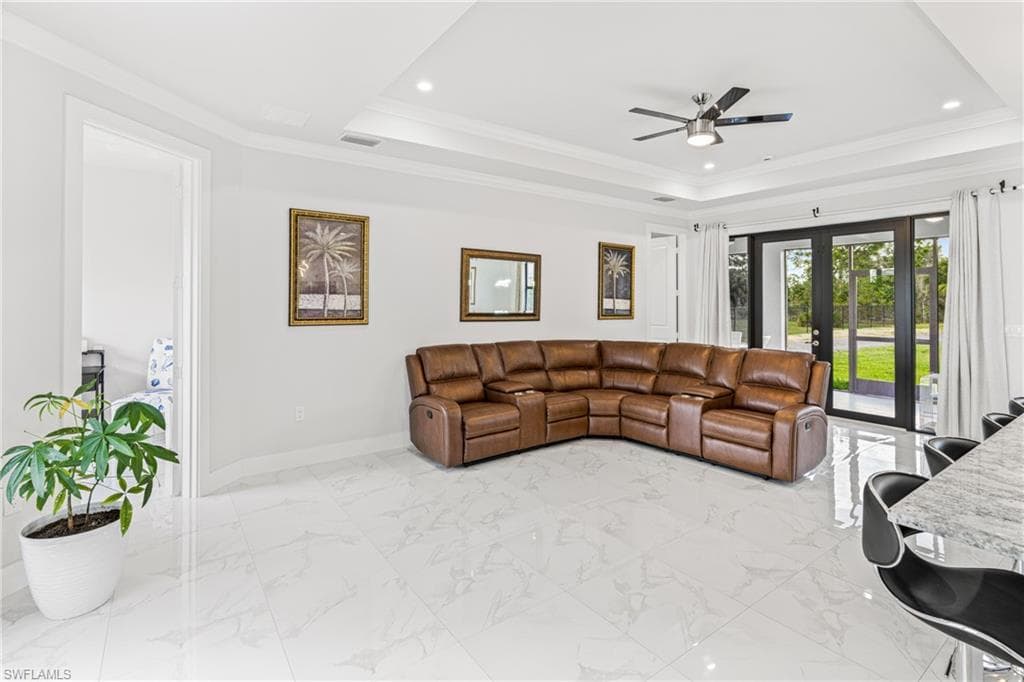 Living area with baseboards, a raised ceiling, visible vents, and crown molding