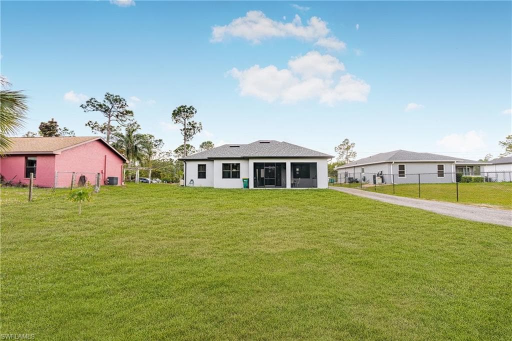 Rear view of property with a lawn and fence