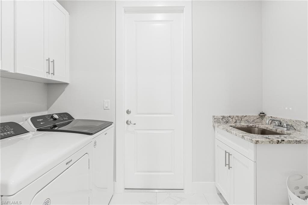 Laundry room with cabinet space, marble finish floor, a sink, and independent washer and dryer