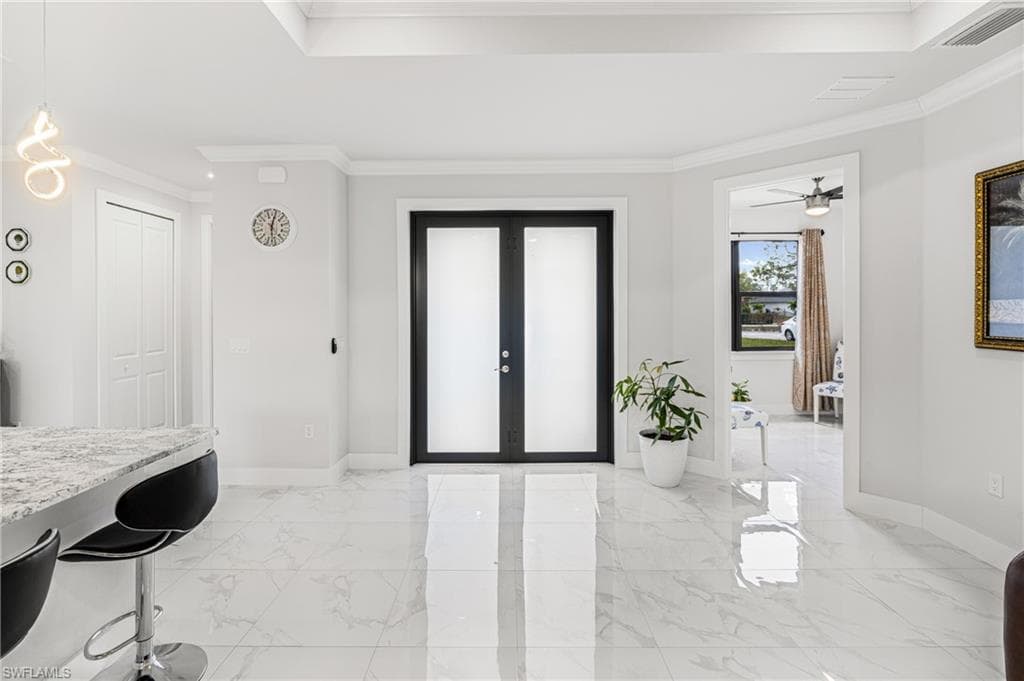 Entrance foyer featuring visible vents, baseboards, marble finish floor, french doors, and crown molding