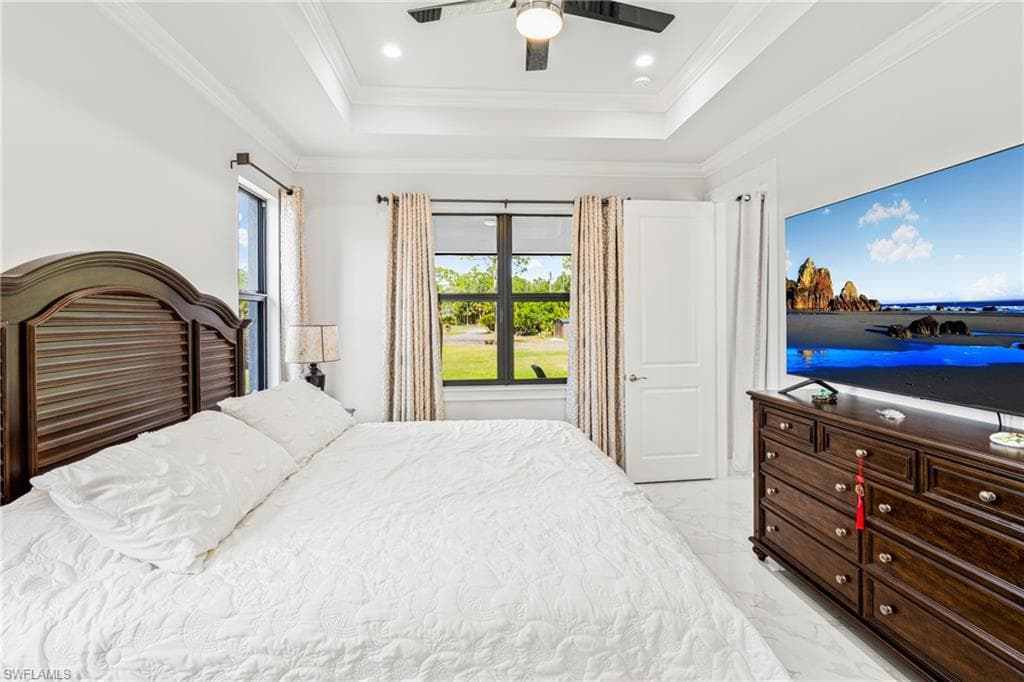 Bedroom featuring a tray ceiling, marble finish floor, crown molding, recessed lighting, and ceiling fan