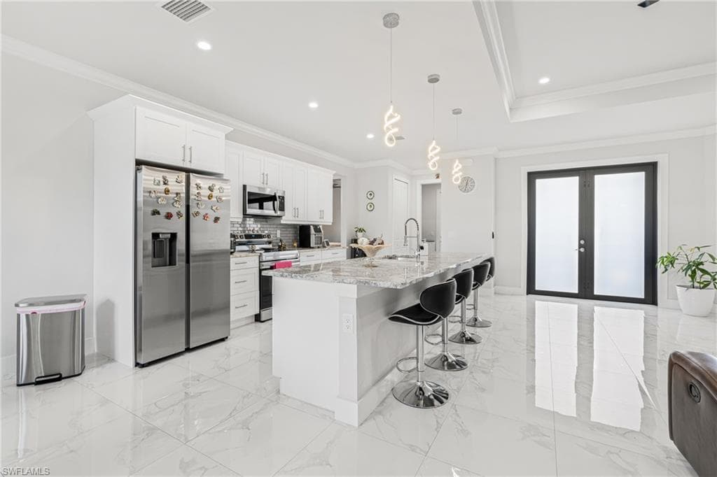Kitchen with marble finish floor, french doors, visible vents, appliances with stainless steel finishes, and ornamental molding