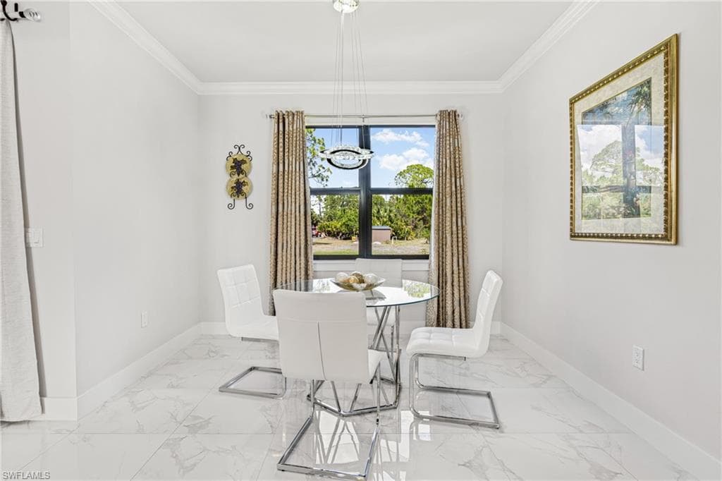 Dining space featuring marble finish floor, crown molding, baseboards, and an inviting chandelier